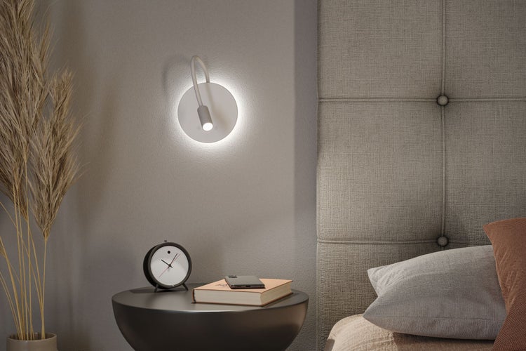 Nachttisch mit Lampe, Wecker, Buch und Smartphone in einem Schlafzimmer