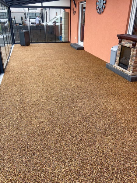 Geräumiger Wintergarten mit nahtlosem Steinteppichboden in Braun und Beige, Glasschiebetüren und einem kleinen dekorativen Kamin.