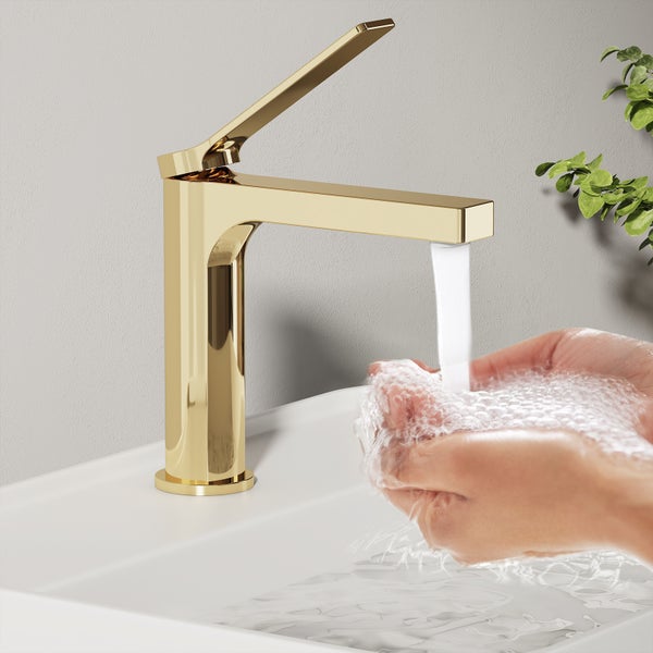 Goldene Waschtischarmatur mit laufendem Wasser und Händen