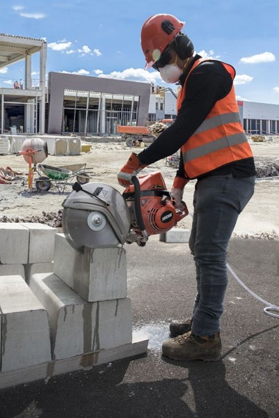 Ein Bauarbeiter schneidet mit einer Steinsäge Steine auf einer Baustelle.
