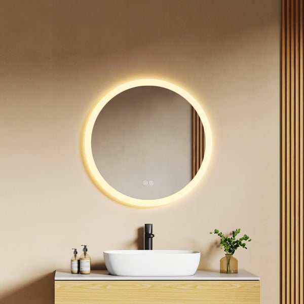 Runder beleuchteter Badezimmerspiegel mit warmweißer Lichtquelle über einem ovalen Aufsatzwaschbecken und schwarzer Armatur.