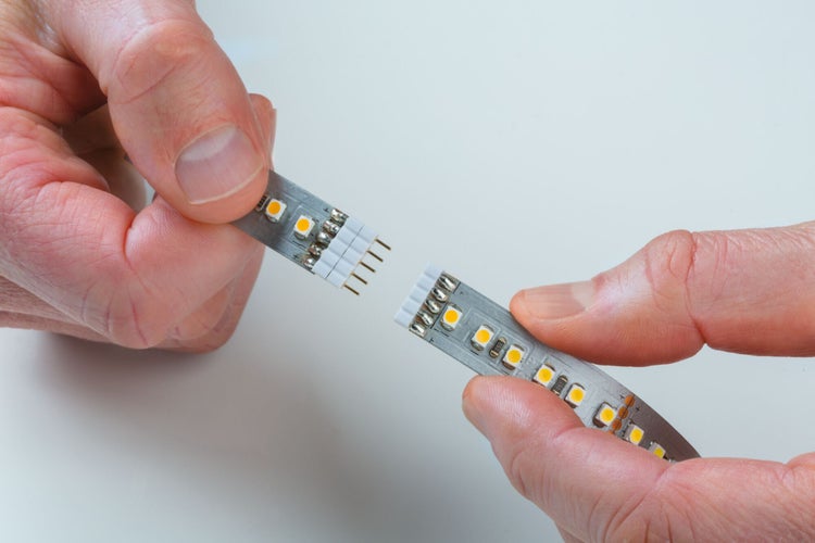 Hände verbinden LED-Streifen mit Stiftleiste