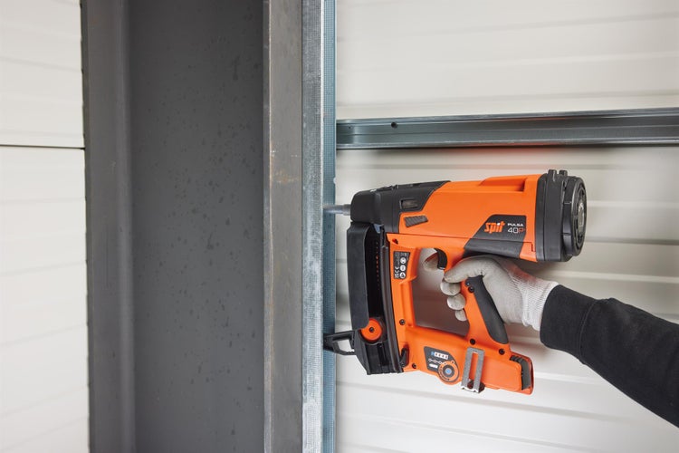 Eine Person benutzt ein Spit Pulsa 40P Gasschussgerät, um ein Metallstück zu befestigen.