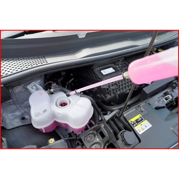 Nachfüllen von Kühlmittel in den Ausgleichsbehälter eines Fahrzeugmotors mit einer Flasche.
