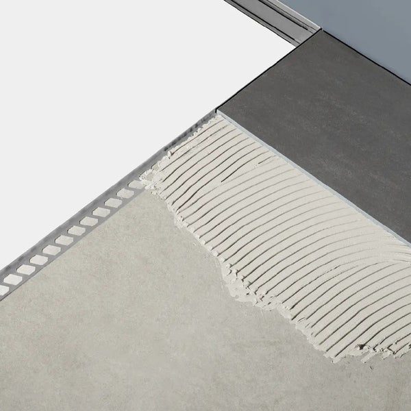 Einbau eines Übergangsprofils aus Metall zwischen einer Fliese und einem niedrigeren Bodenbelag mit Fliesenkleber.