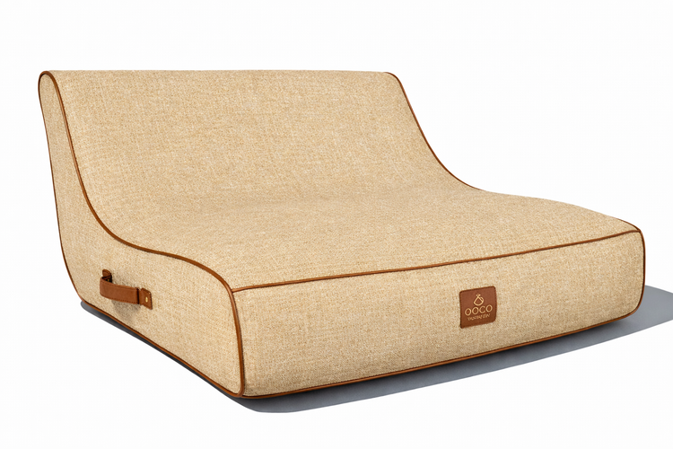 Ergonomisches beige Hundebett aus Webstoff mit brauner Lederpaspel, Griff und OOCO Logo.