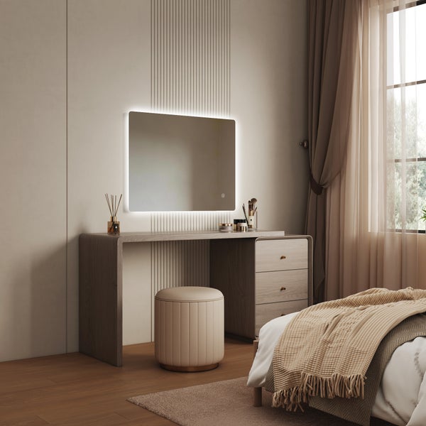Moderner Schminktisch mit beleuchtetem Wandspiegel in einem Schlafzimmer mit gepolstertem Hocker und Holzschubladen.