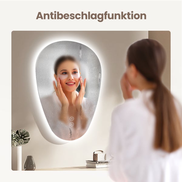 Ovaler Badezimmerspiegel mit LED Beleuchtung und Antibeschlagfunktion zeigt eine Frau mit Augenmasken, die sich im Spiegel betrachtet.
