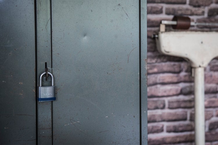 ABUS Vorhangschloss an einem grauen Metallspind vor einer Ziegelwand