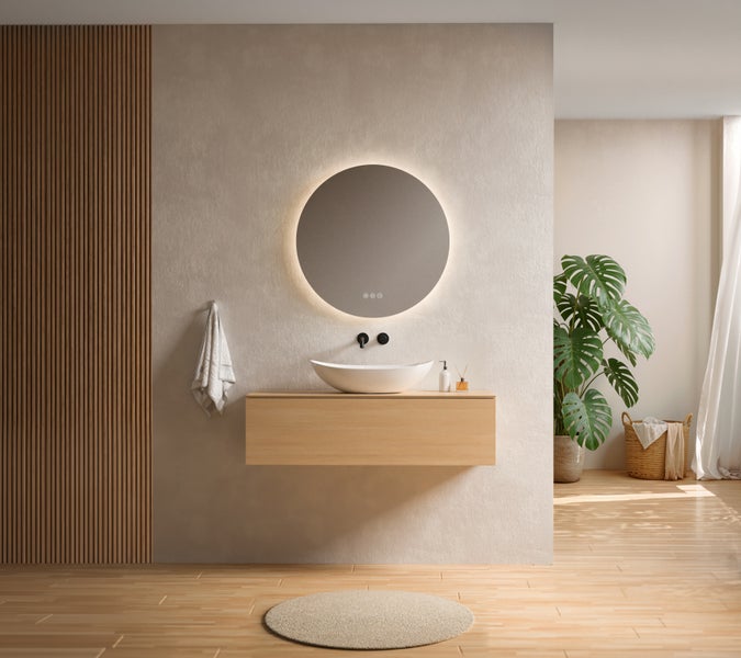 Modernes Badezimmer mit holzverkleideter Wand, rundem LED Spiegel, Aufsatzwaschbecken auf Holzhängeschrank, Zimmerpflanze und weichem Holzboden.