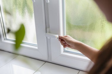 Weiße Fenstersicherung für zweiflügelige Fenster wird mit einem Schlüssel bedient.