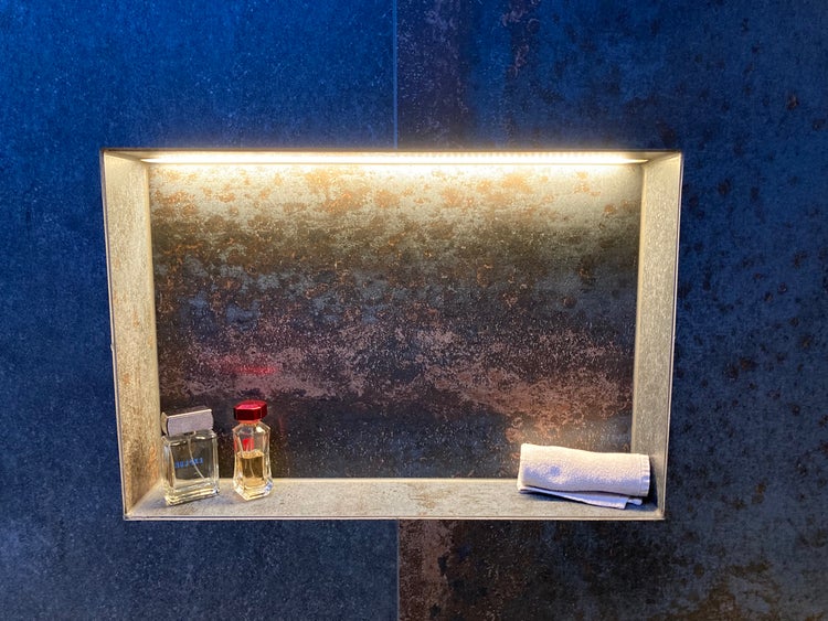 Beleuchtete Wandnische im Badezimmer mit Kosmetikartikeln und einem Handtuch