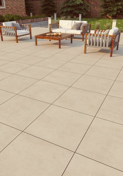 Terrasse mit großformatigen Feinsteinzeug-Bodenplatten in Sandoptik und modernen Lounge-Gartenmöbeln aus Holz mit weißen Polstern.