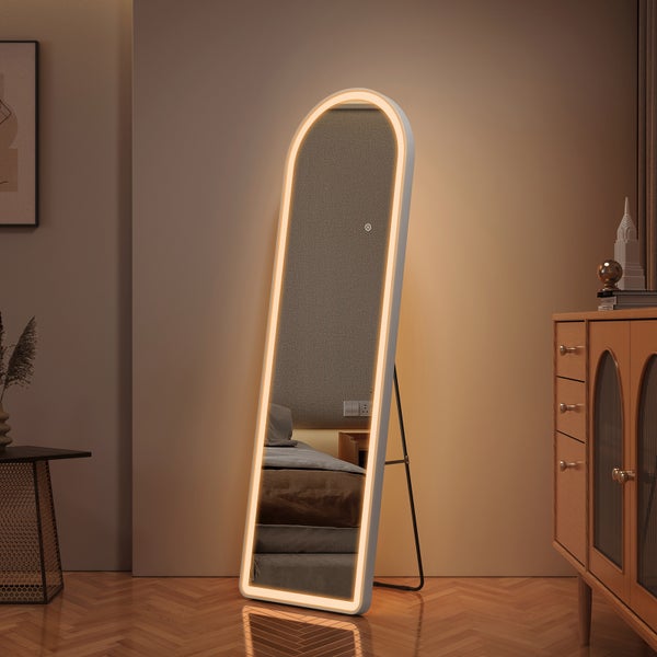 Freistehender, bogenförmiger Ganzkörperspiegel mit integriertem LED-Leuchtring in einem modern eingerichteten Zimmer mit Holzmöbeln.