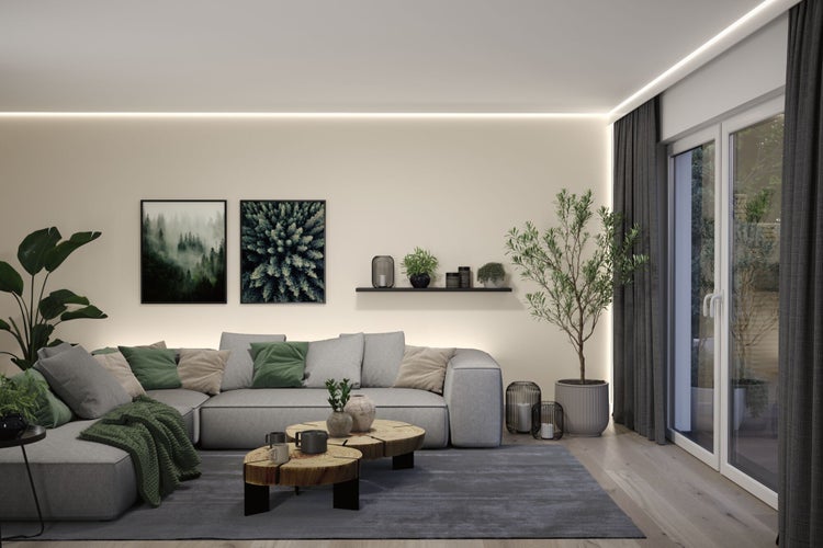Wohnzimmer mit grauer Eckcouch, Holztischen und Pflanzen für eine gemütliche Atmosphäre.