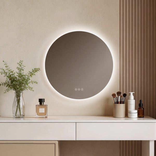 Moderner, runder LED-Spiegel mit Hintergrundbeleuchtung und Touch-Bedienung über einem weißen Schminktisch mit Badaccessoires und Dekoration.