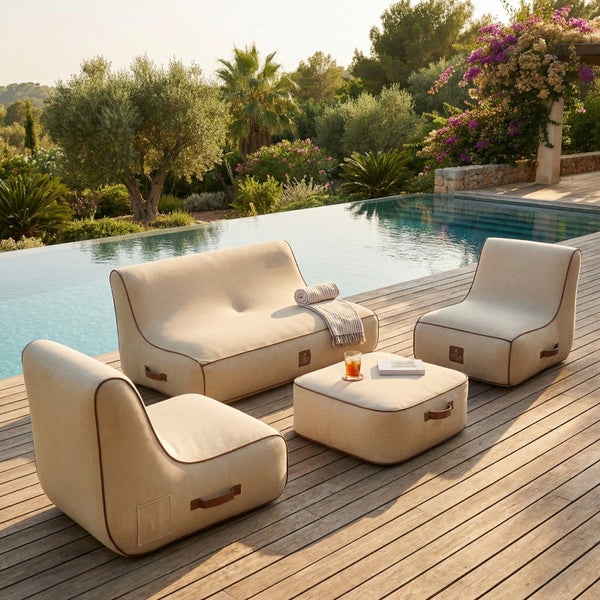 Modernes beige Garten-Lounge-Set bestehend aus Sofa, Sesseln und Hocker auf einer Holzterrasse am Pool.