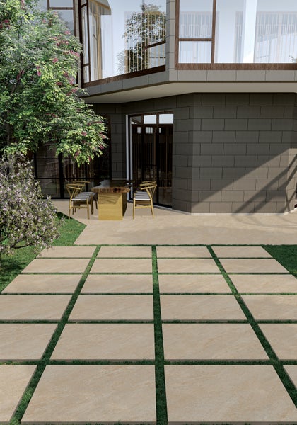 Großformatige Terrassenplatten aus Feinsteinzeug, verlegt im Rasen und auf der Terrasse vor einem modernen Wohnhaus mit Gartenmöbeln.