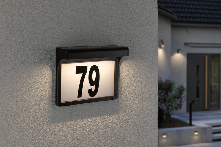 Beleuchtetes Hausnummernschild mit der Nummer 79 an der Wand