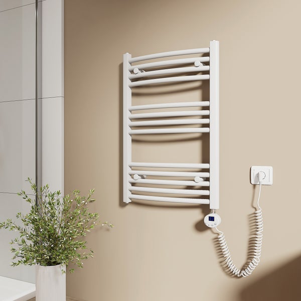 Elektrischer Handtuchheizkörper mit Thermostat an einer Wand im Badezimmer neben einer Pflanze.