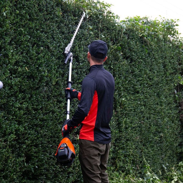 Eine Person schneidet eine Hecke mit einer Akku-Heckenschere.