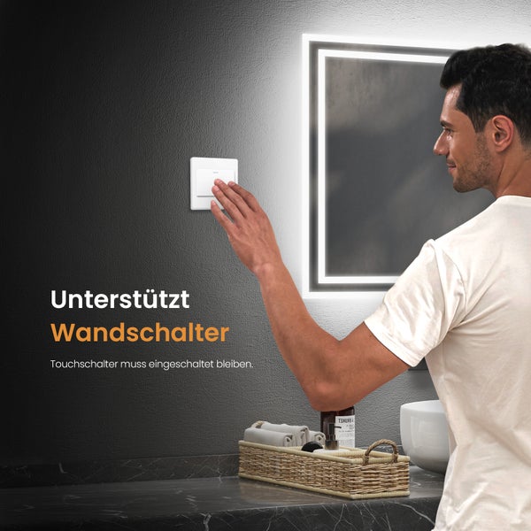 Ein Mann bedient einen Lichtschalter in einem Badezimmer mit beleuchtetem Spiegel