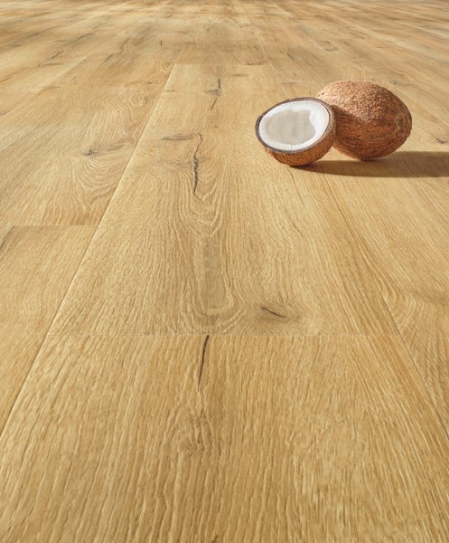 Laminatboden in Eichen-Optik mit Holzmaserung und Ästen, darauf liegt eine halbierte Kokosnuss.