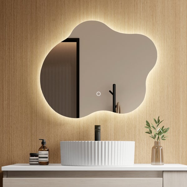 Moderner Badezimmerspiegel in unregelmäßiger Form mit LED-Hintergrundbeleuchtung und Touch-Sensor auf einer Holzwand über einem Aufsatzbecken.
