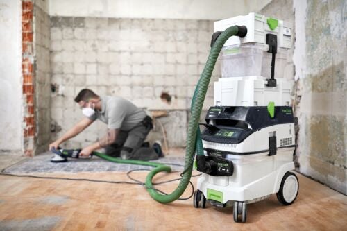 Handwerker schleift Holzboden mit Schleifmaschine, angeschlossen an ein Festool Absaugmobil mit Systainer-Turm auf einer Baustelle.