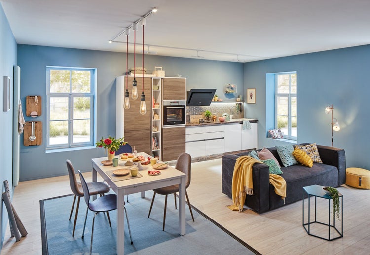 Offene Küche mit Essbereich und Wohnzimmer in einem Raum mit Küchenzeile, Esstisch und Sofa