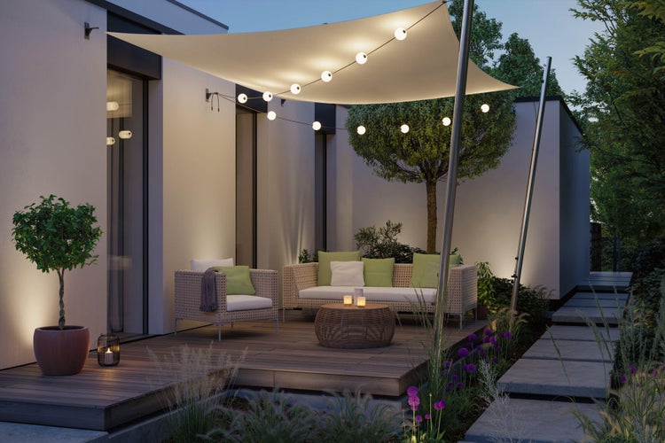 Terrasse mit Sonnensegel, Rattansitzgruppe und Beleuchtung für ein gemütliches Ambiente