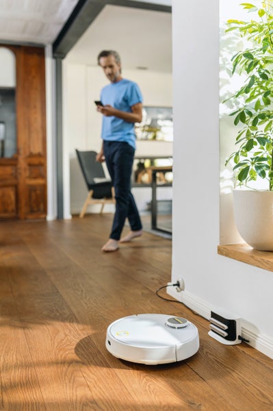 Saugroboter mit Ladestation auf Holzboden in modernem Wohnraum