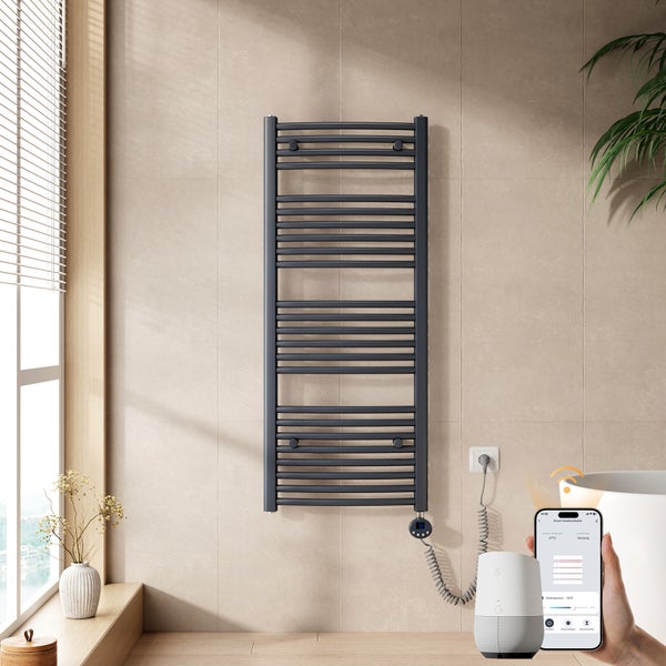 Wandmontierter elektrischer Handtuchheizkörper mit Steuerung per Smartphone und Smart-Speaker in einem modernen Badezimmer.