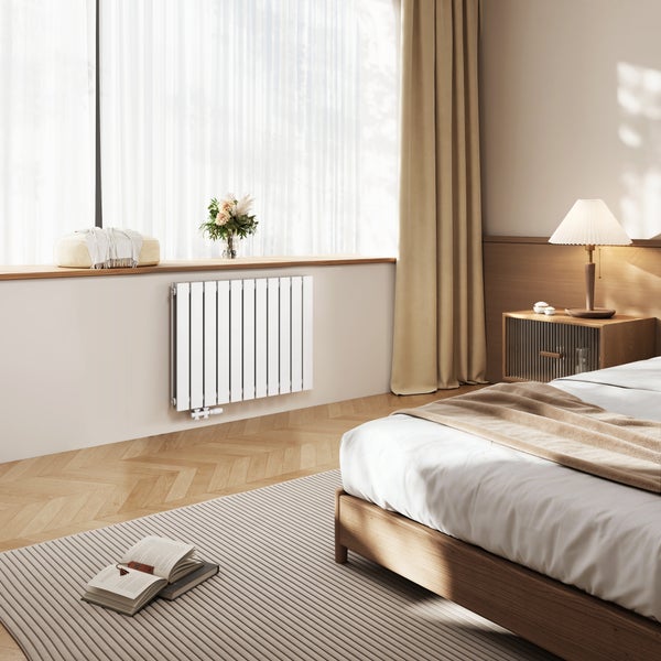 Helles Schlafzimmer mit Heizkörper unter dem Fenster, Bett und Teppich.