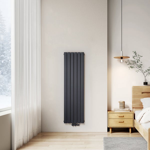 Vertikaler Heizkörper an der Wand in einem hellen Schlafzimmer.