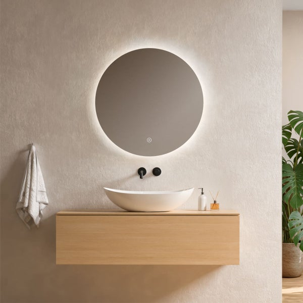 Modernes Badezimmer mit rundem LED-Spiegel, weißem Aufsatzwaschbecken auf einem Holz-Waschtischunterschrank und schwarzer Wandarmatur.