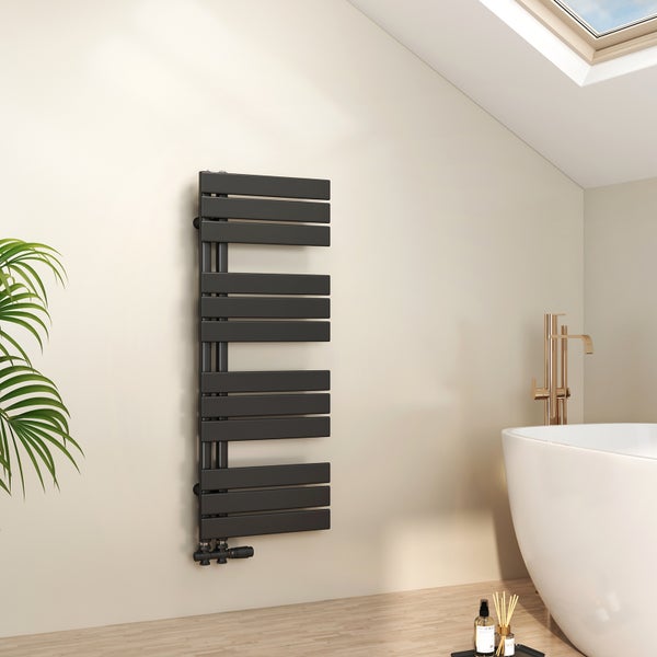 Moderner schwarzer Design-Heizkörper neben einer weißen freistehenden Badewanne mit goldener Armatur in einem hellen Badezimmer.