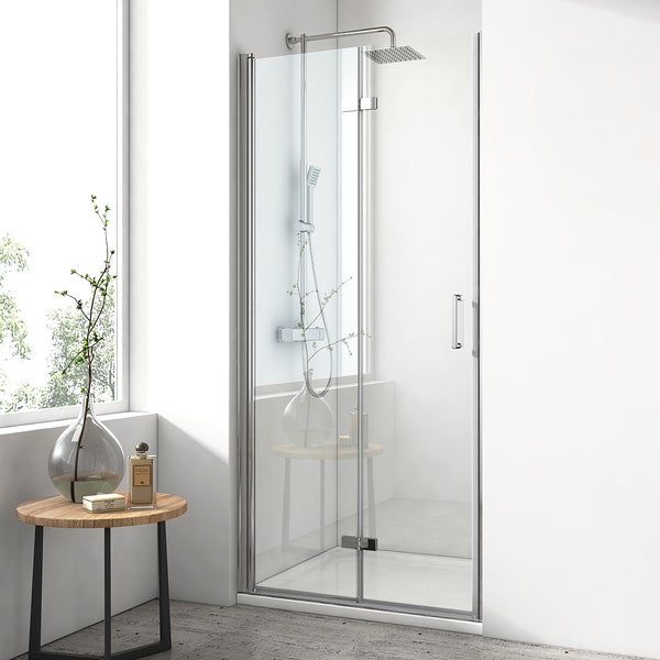 Moderne Nischendusche mit Glastür und Chrombeschlägen in einem hellen Badezimmer mit Regenduschkopf, Fenster und dekorativem Beistelltisch.