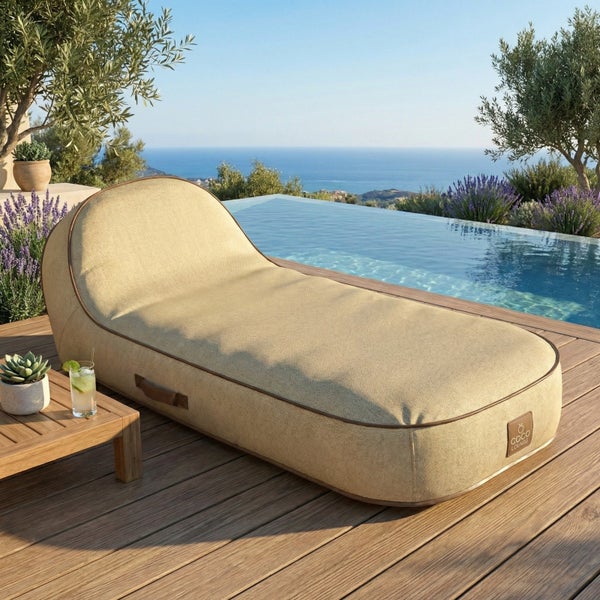 Moderne Outdoor-Lounge-Liege aus Webstoff auf einer Holzterrasse neben einem Pool, mediterrane Umgebung mit Meerblick.
