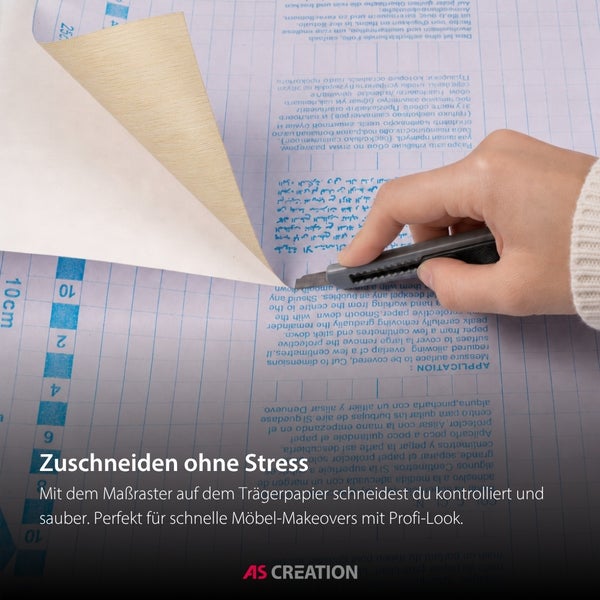 Hand beim Zuschneiden einer selbstklebenden Folie mit einem Cuttermesser auf einem Trägerpapier mit Maßraster.