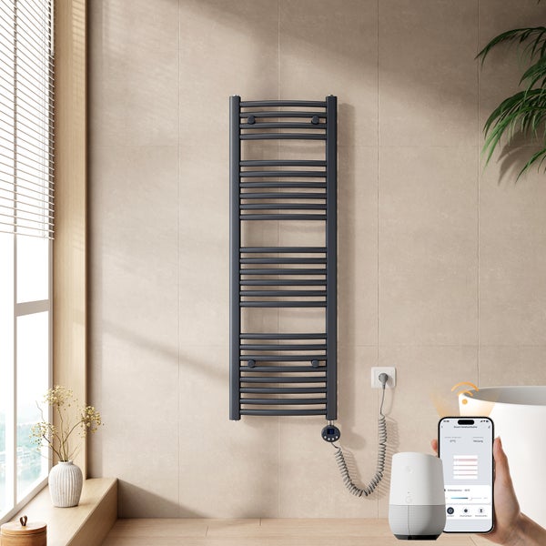 Moderner Badheizkörper in Anthrazit an einer beigefarbenen Wand, steuerbar über Smartphone-App und Smart Speaker im Badezimmer.