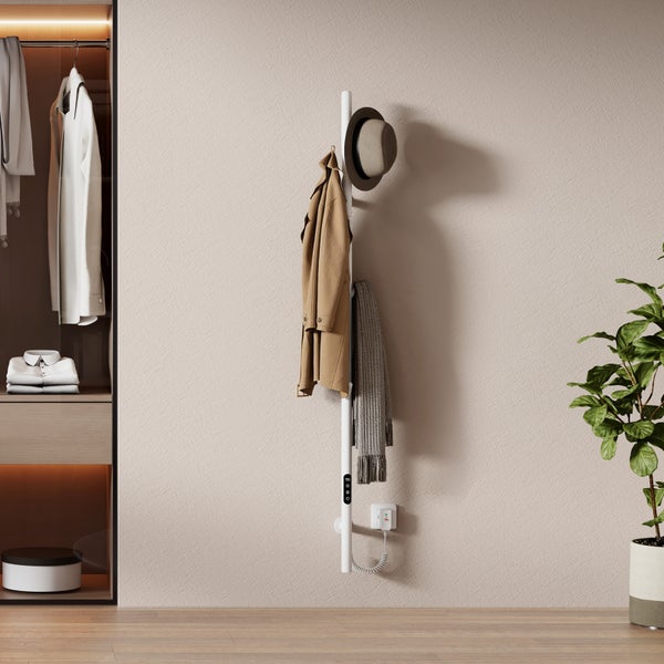 Elektrischer Design Handtuchheizkörper als Garderobenstange an einer Wand montiert mit Kleidung und Accessoires in modernem Wohnbereich.