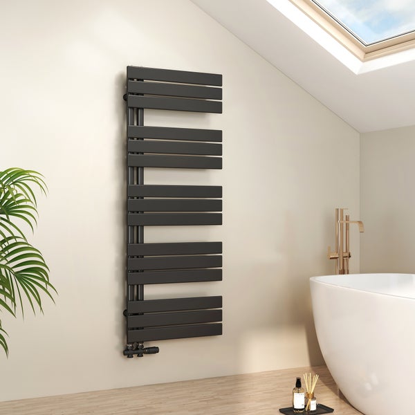 Moderner anthrazitfarbener Badheizkörper an einer hellen Wand in einem hellen Badezimmer mit freistehender Badewanne und goldener Armatur.