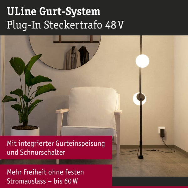 Uline Gurtsystem Stehlampe mit zwei Leuchten neben Sessel und Zimmerpflanze