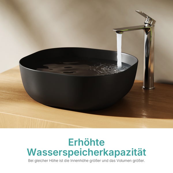 Schwarzes Aufsatzwaschbecken mit erhöhter Wasserspeicherkapazität auf einer Holzplatte mit fließendem Wasser aus einer Armatur.