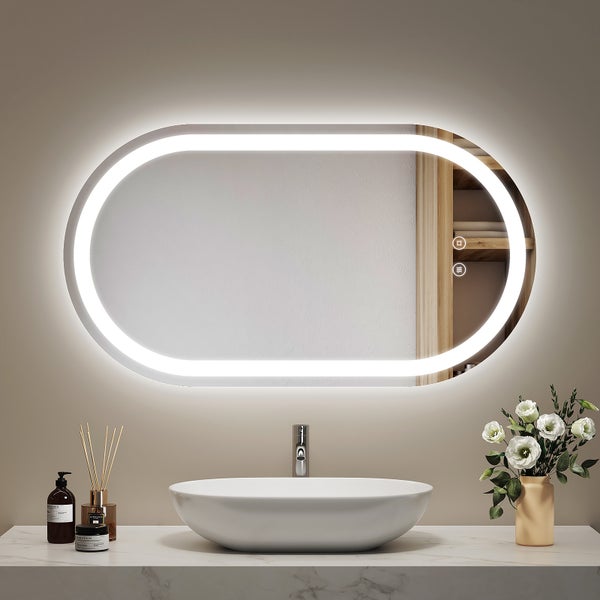 Ovaler Badezimmerspiegel mit integrierter LED Beleuchtung und seitlichem Regal, montiert über einem Aufsatzwaschbecken auf Marmor Waschtischplatte.