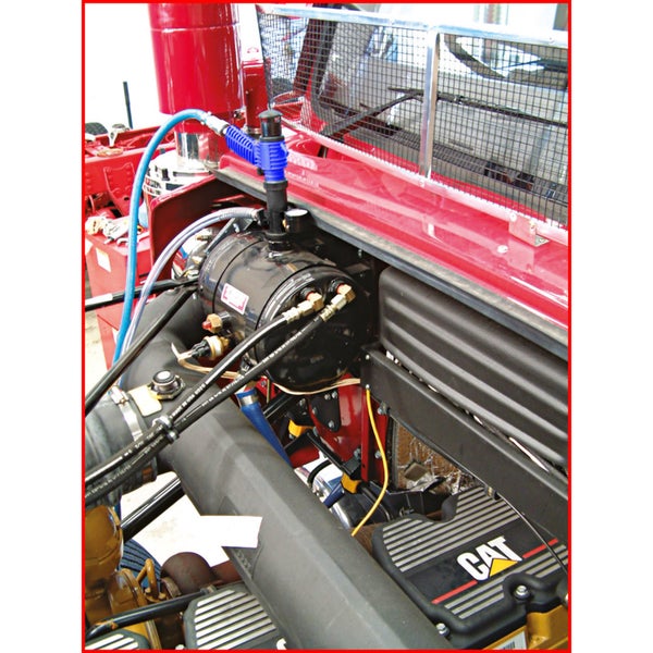 Motorraum eines schweren Nutzfahrzeugs mit Caterpillar Motorblock und installierter Druckluftanlage mit Schläuchen.