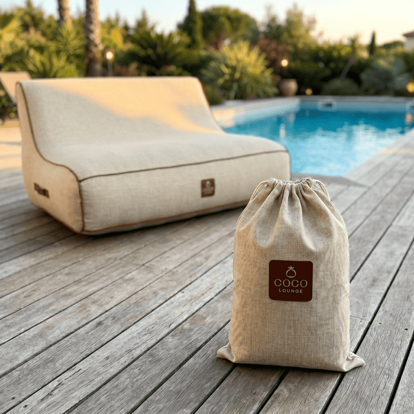 Coco Lounge Garten-Loungesessel aus strukturiertem Stoff auf einer Holzterrasse am Pool mit Coco Lounge Logo auf dem Aufbewahrungsbeutel.
