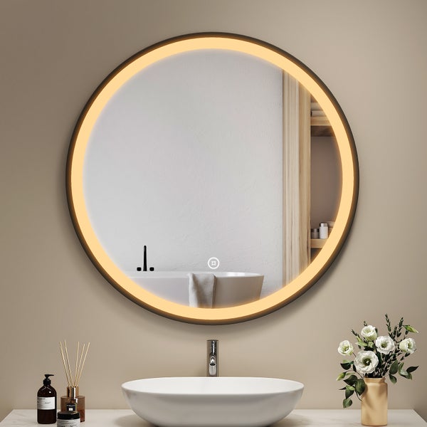 Runder Badezimmerspiegel mit umlaufender LED Beleuchtung und Touch Sensor über einem modernen Waschbecken auf einem Waschtisch mit Dekoration.