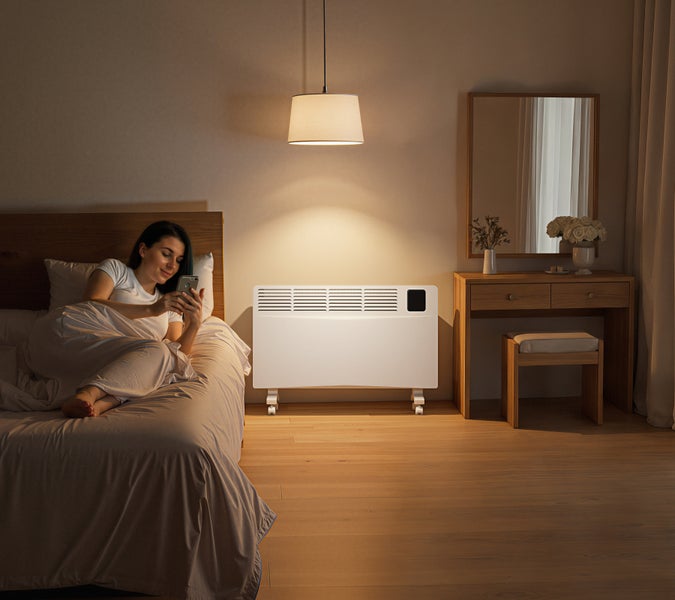 Schlafzimmer mit Frau im Bett und einem weißen Konvektor-Heizgerät